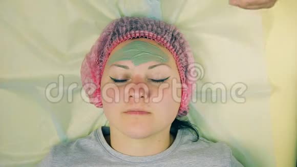 时光飞逝化妆师的男人的手在女人的脸上放了一个蓝色粘土制成的液体面具视频的预览图