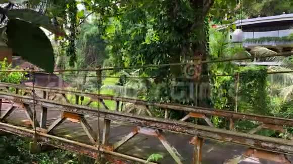绿色丛林和度假别墅之间的锈桥视频的预览图