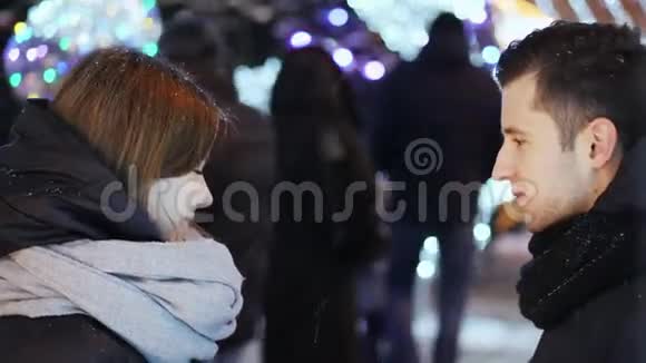 和一对美丽的情侣在雪下约会男人送花和一份新年礼物给女人视频的预览图