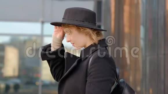 年轻漂亮的金发女孩戴着一顶黑色帽子绿眼睛向上看着小屋的周围年轻的杜瓦什卡视频的预览图