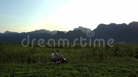 一对夫妇骑着滑板车在田野间对抗高山空中视频的预览图