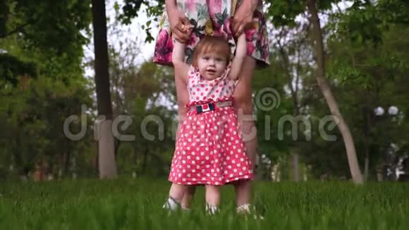 妈妈在夏天公园里牵着小女儿的手女孩在户外和妈妈玩耍时大笑视频的预览图