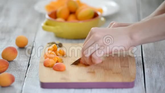 女性用刀子在切割板上切杏的特写烹饪素食视频的预览图