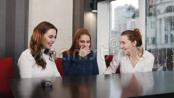 朋友们在酒吧见面三个年轻的女人在笑服务员端来一杯茶视频的预览图
