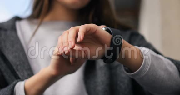 年轻漂亮的女人用手指在智能手表可穿戴设备的触摸屏上做各种手势聪明的视频的预览图