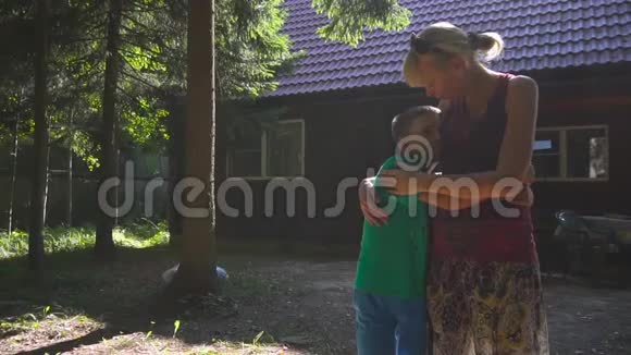 妈妈在他们夏天的房子前拥抱和亲吻儿子视频的预览图