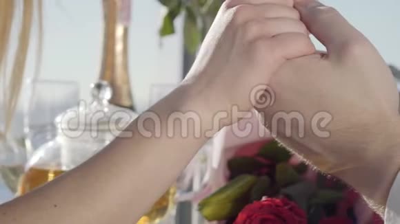 日期未确认的夫妇年轻夫妇手牵手坐在餐桌上手捧玫瑰花束视频的预览图