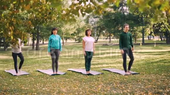 瑜伽学生在公园户外课堂上在专业教练的指导下做平衡练习视频的预览图