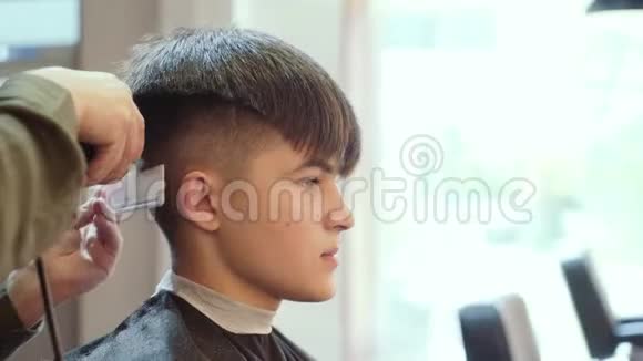 男士美容师理发店剪发在年轻人的头上剪发器视频的预览图