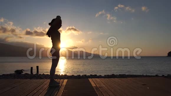 4k日落时的女性剪影在海边慢动作练习能量视频的预览图