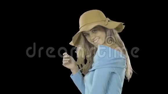 漂亮的女人留着长发戴着帽子站在侧面微笑着用一只眼睛眨着眼睛时尚射击视频的预览图