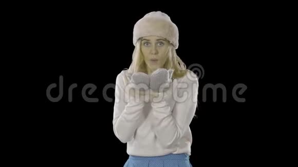 美丽迷人的年轻女子戴着一顶帽子戴着手套把手掌放在一起微笑着吹走视频的预览图