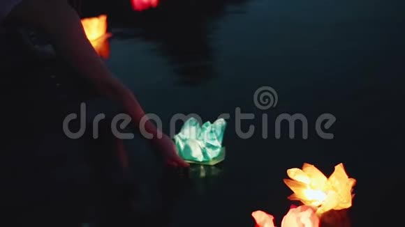 女孩在水面上发射手电筒晚上在水上放着花灯浪漫的夜晚美丽的漂浮视频的预览图