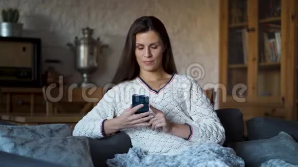 沙发上的美女裹着毯子在电话里聊天视频的预览图