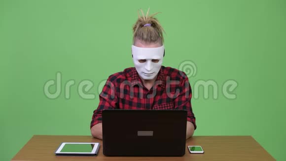 黑皮斯特人戴着面具当黑客同时还要对木制桌子进行多重任务视频的预览图