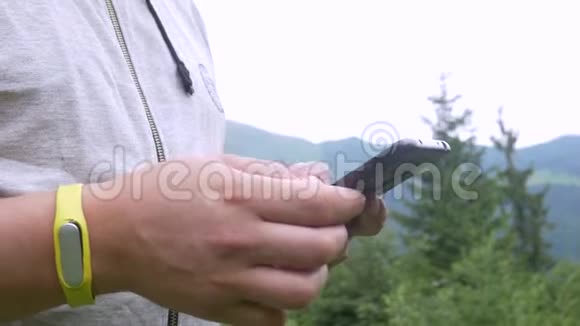 在山林背景下使用智能手机无法辨认的男性手视频的预览图