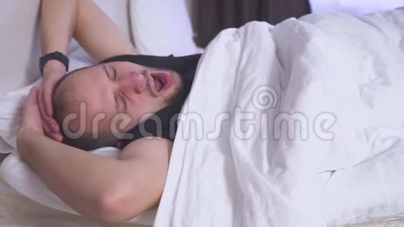 睡觉的人在双人床上醒来侧视中镜头视频的预览图