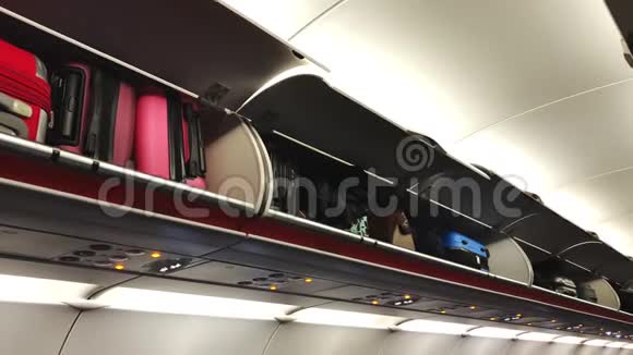 飞机上货架上陈列着明亮的手提箱典型客机经济舱客舱视频的预览图