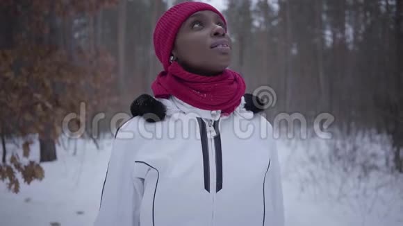 非裔美国女孩走在冬季森林抬头穿暖和夹克的漂亮女孩花时间在户外慢慢视频的预览图