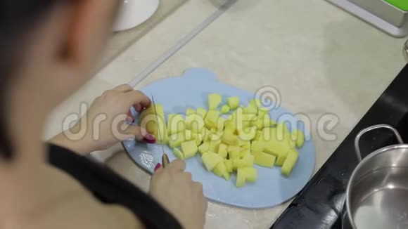 女人在蓝色砧板上切土豆视频的预览图
