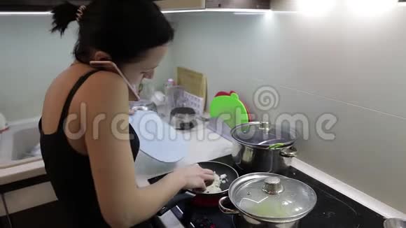美丽的白种人女人一边做饭一边打电话视频的预览图
