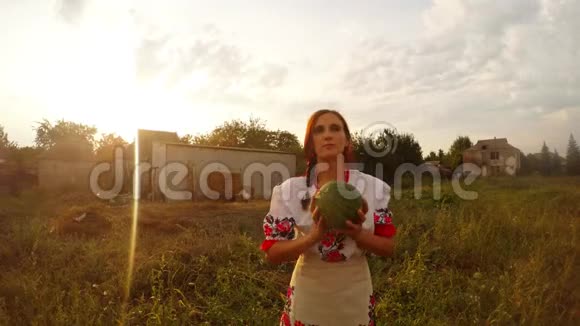 一位穿着传统的乌克兰民俗服装的年轻女子扔了一个西瓜给相机然后把它放回手中视频的预览图