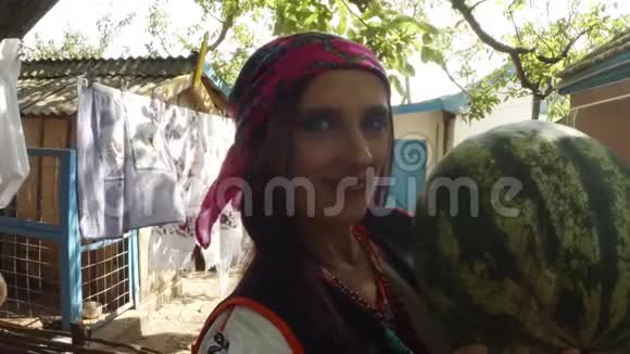 一位身穿乌克兰民俗服装的年轻女子手里拿着一个西瓜手里拿着一个在农村院子里洗衣服的西瓜视频的预览图