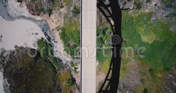 俯视无人驾驶飞机从行驶在比克斯比溪桥溪桥揭示了惊人的美丽的自然和海洋周围视频的预览图