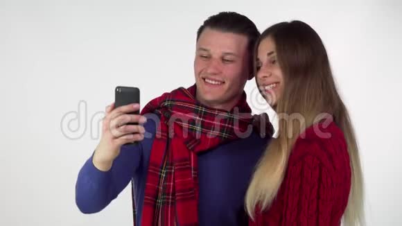 可爱的夫妇穿着温暖舒适的衣服一起用智能手机自拍视频的预览图