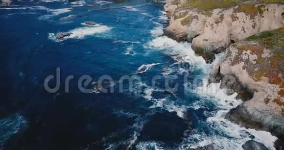 在美丽的海洋海岸上空飞翔的无人机在夏天的大苏尔风光加州泡沫般的海浪拍打着巨大的岩石视频的预览图