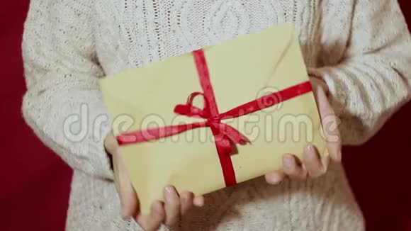 漂亮的女孩手里拿着一个带有红色丝带的礼物信封视频的预览图