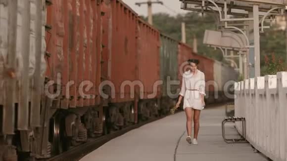 在火车站的火车轨道附近行走的女人美自由夏日旅行理念视频的预览图