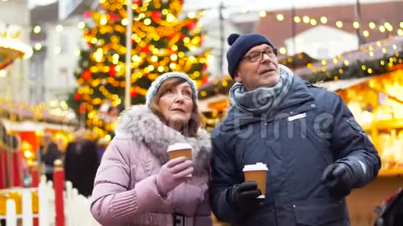 在圣诞市场上喝热饮料的老夫妇视频的预览图