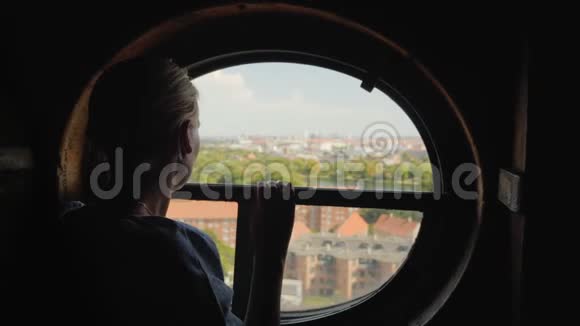 丹麦哥本哈根市屋顶上一个女人在一扇圆窗里张望的剪影视频的预览图