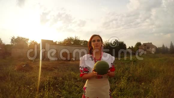 一个穿着乌克兰民俗服装的女孩向镜头扔西瓜从镜头后面接住一个飞来的西瓜视频的预览图