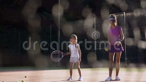 英俊的女教练投掷球和小女孩击球和失踪视频的预览图