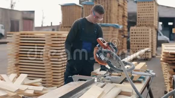 木工工人佩戴施工护目镜使用木切割机男人切木木板视频的预览图