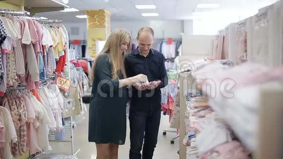 孕妇和丈夫在一家儿童服装店幸福的家庭给宝宝选衣服视频的预览图
