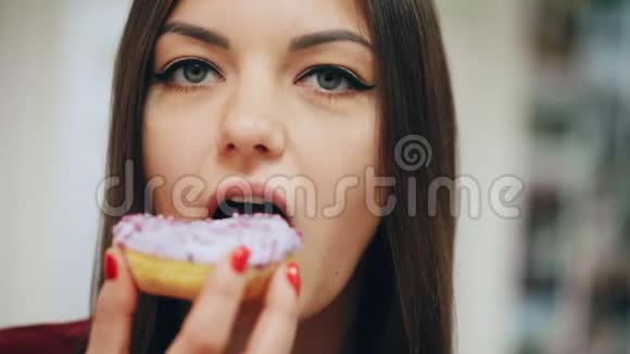 一幅美丽的快乐女孩吃甜甜圈在工作中享受零食的特写照片视频的预览图