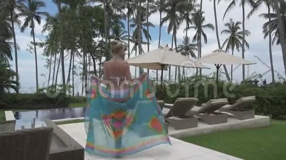 镜头移向年轻苗条的女人比基尼去印度尼西亚巴厘岛热带的游泳池视频的预览图