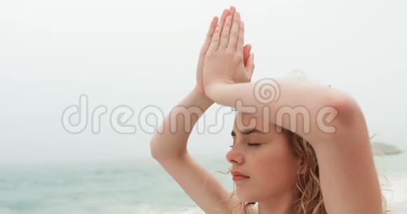 在海滩上做瑜伽的白人妇女的侧视4k视频的预览图