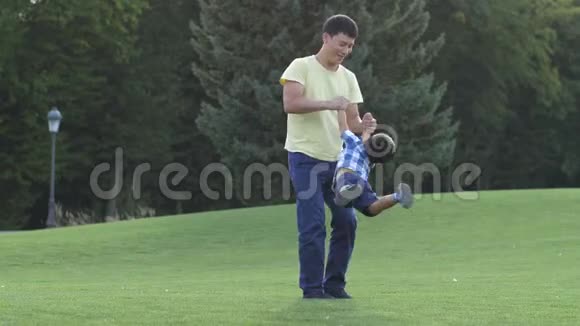 快乐的亚洲父亲在草地上旋转他可爱的儿子视频的预览图