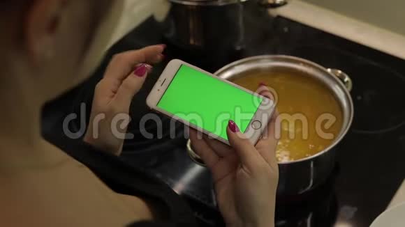 一位女士拿着一部绿色屏幕的智能手机正在煮汤视频的预览图