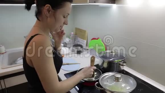 美丽的白种人女人一边做饭一边打电话视频的预览图