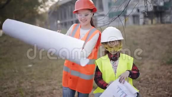 小建筑工人两个儿童防护头盔和背心研究技术文件视频的预览图