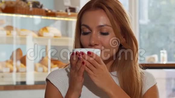幸福的姜发女人开心地笑着喝着美味的咖啡视频的预览图