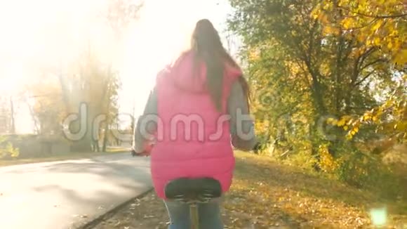 小女孩骑自行车在秋天公园的路上微笑着慢动作视频的预览图