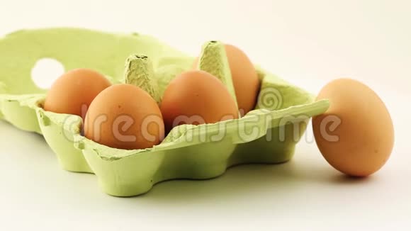 新鲜的棕色鸡蛋在鸡蛋纸箱内和旁边旋转在白色上视频的预览图