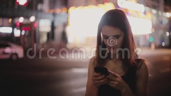美丽的中等镜头快乐的欧洲当地妇女环顾四周使用智能手机应用程序在黑暗的纽约街微笑视频的预览图