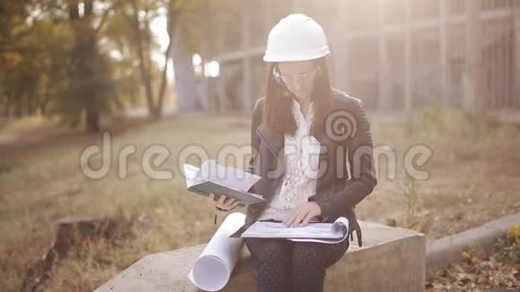 建筑工地戴安全帽和安全眼镜的女学生检查技术文件视频的预览图